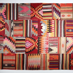 Op de afbeelding: Een kleurrijk patchwork tapijt met geometrische patronen in tinten rood, blauw, groen en geel. Het tapijt is gemaakt van geweven wol en heeft een traditioneel Turks ontwerp.