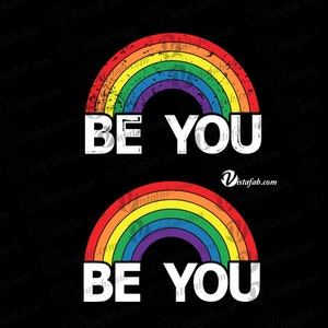 May include: Two rainbow arches with a distressed, vintage look. The text "BE YOU" is written in white letters on a black background.