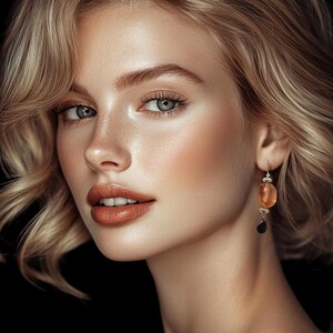 May include: A woman with blonde wavy hair and light eyes. She is wearing a pair of gold earrings with amber and black stone pendants. The background is black.