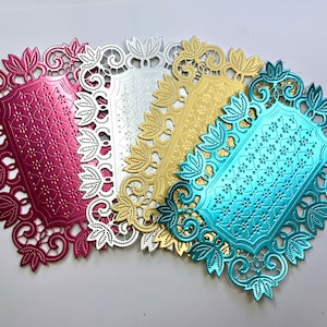 May include: Four rectangular metal die-cut shapes in magenta, silver, gold, and turquoise. Each piece features a central panel with a repeating floral pattern surrounded by an intricate, lacy border with stylized leaf motifs along the edges.
