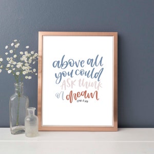 Könnte beinhalten: Ein gerahmter Druck mit weißem Hintergrund und einem blauen, rosa und orangenen inspirierenden Zitat, das "above all you could ask think or dream" lautet, mit dem Schriftzitat "EPH 3:20" darunter.