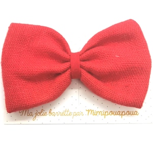 Peut inclure: Un grand nœud en tissu rouge avec une surface texturée. Le nœud est sur un fond blanc avec du texte doré qui dit "Ma jolie barrette par Mimipouapoua".