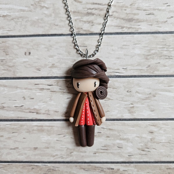 Collier petite fille brune, haut rouge et veste marron.