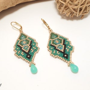 May include: A pair of green and gold beaded earrings with a teardrop-shaped green stone hanging from each earring.