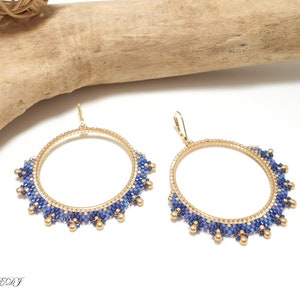 May include: A pair of gold hoop earrings with blue and gold beads. The earrings are large and have a circular shape.