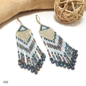 May include: A pair of long, beaded earrings with a geometric design. The earrings are made with silver, blue, and white beads and have a fringe-like bottom.
