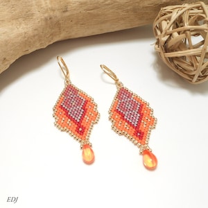 May include: A pair of orange, pink, and gold beaded earrings with a teardrop-shaped orange crystal dangle.