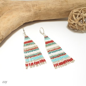 May include: A pair of long, beaded earrings with a white, turquoise, and red striped pattern. The earrings have a silver hook closure and a fringe of beads at the bottom.