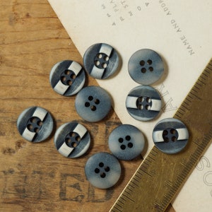 May include: Assortment of ten black and white striped buttons with a blue center. The buttons have four holes each.