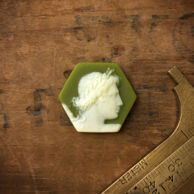 May include: A green hexagonal cameo with a white cameo of a woman's profile wearing a wreath.