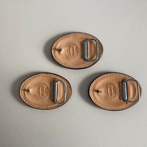 May include: Three oval-shaped leather belt buckles with a silver metal buckle and the text "CUR LAKOTA CRAFTING" embossed on each.