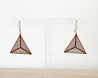 May include: A pair of brown triangle earrings with a geometric design. The earrings are hanging from a clear acrylic earring stand.
