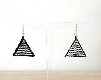 May include: A pair of black triangle earrings with a mesh design. The earrings are suspended from silver-colored ear wires. The earrings are displayed on a clear stand against a white background.