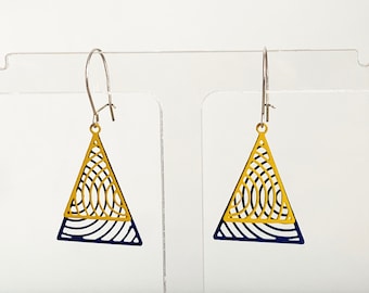 May include: A pair of triangle-shaped earrings with a geometric design. The earrings are yellow with a blue outline and a blue stripe across the middle.