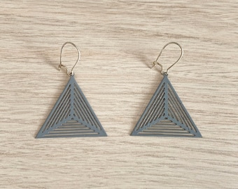 May include: A pair of gray triangle earrings with a geometric pattern. The earrings have a silver hook closure.