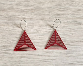 May include: A pair of red triangle earrings with a geometric design. The earrings have a silver hook closure.