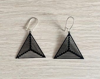 May include: A pair of black triangle earrings with a geometric design. The earrings have a silver hook closure.