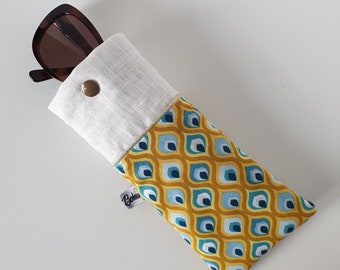 May include: A white linen and yellow, blue, and green patterned fabric sunglasses case with a button closure. The case has a small label that says "Bohemian".