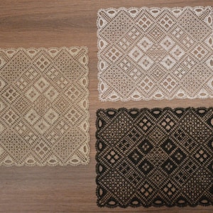 May include: Three square lace doilies in beige, white, and black. Each doily features a geometric diamond pattern and a scalloped edge. The doilies are displayed on a wooden surface.