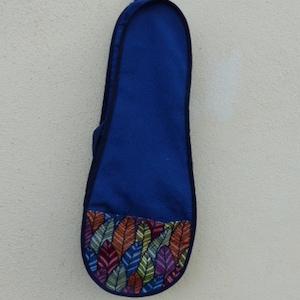 Könnte beinhalten: Eine blaue Ukulelen-Tasche mit einem bunten Blatt-Muster am Boden.
