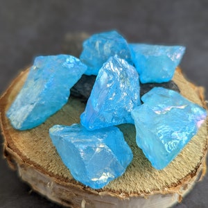 Op de afbeelding: Een groep van zes lichtblauwe, iriserende kristallen op een houten oppervlak.