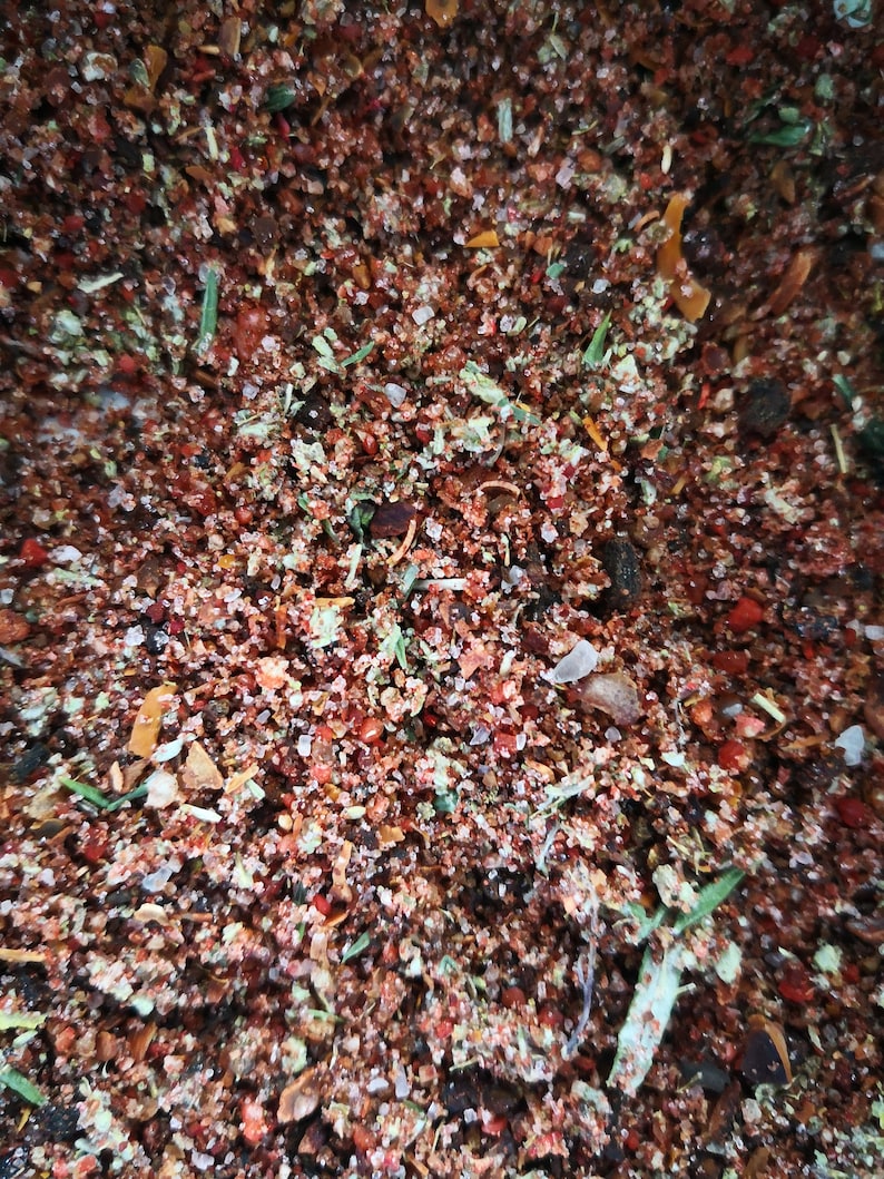 May include: A close-up of a mixture of dried herbs and spices, including red pepper flakes, salt, and dried herbs.