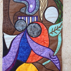 Puede incluir: Colcha de arte abstracto con una variedad de colores y formas, incluyendo morado, azul, naranja, amarillo y marrón. La colcha está hecha de retazos de tela cosidos juntos en un estilo patchwork.