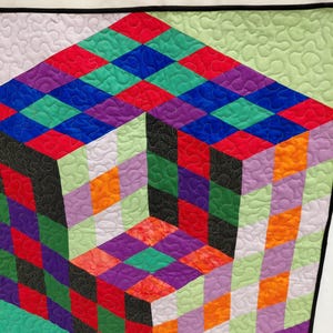 May include: A colorful geometric quilt featuring a 3D cube design. The quilt showcases a vibrant array of colors, including red, green, blue, purple, orange, and black, arranged in a diamond pattern. The quilt is bordered with a black binding.