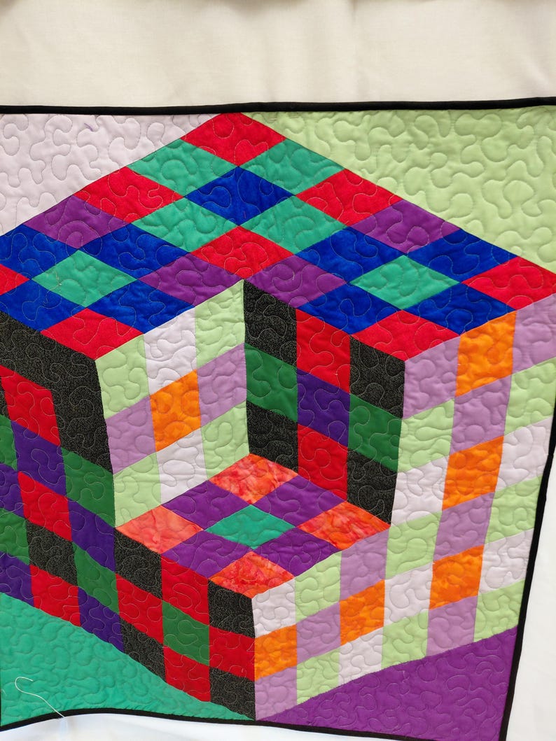 May include: A colorful geometric quilt featuring a 3D cube design. The quilt showcases a vibrant array of colors, including red, green, blue, purple, orange, and black, arranged in a diamond pattern. The quilt is bordered with a black binding.