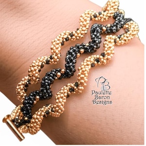 Puede incluir: Una pulsera de cuentas con tres hebras onduladas. La pulsera presenta cuentas doradas y negras, con un cierre dorado. El texto "Paulette Baron Designs" es visible en la imagen.