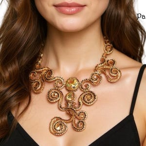 May include: A bronze-toned statement necklace featuring intricate coiled wire patterns and central faceted crystals. The design includes the text Paulette Baron Designs Kits & Pattern. The necklace is worn over a black spaghetti strap top.