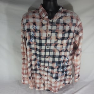 May include: A white and black checked flannel shirt with blue text that reads "Peace Love Respect" and "We Live For Peace".