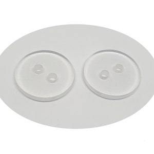 Peut inclure: Deux boutons en plastique transparent avec deux trous chacun.