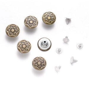 Peut inclure: Un ensemble de 5 boutons en métal doré antique avec un motif floral décoratif, ainsi que 7 boutons pression en métal argenté.