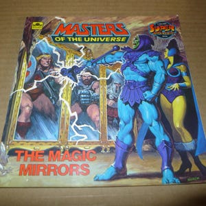 May include: A vintage "Masters of the Universe" comic book cover. The cover features Skeletor, He-Man, and other characters in a dynamic action scene. The title "The Magic Mirrors" is prominently displayed in red text.