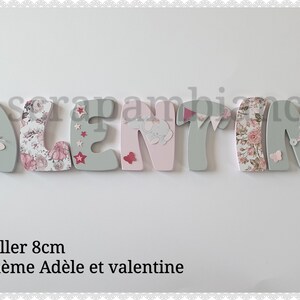 Peut inclure: Neuf lettres en bois épellées "VALENTINE" en rose et gris avec des embellissements floraux et animaliers. Les lettres mesurent 8 cm de haut et sont conçues pour être collées ensemble.