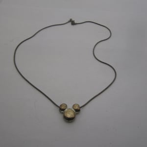 以下が含まれることがあります： 銀色のチェーンネックレスに、金色のミッキーマウスの頭のペンダントが付いている。