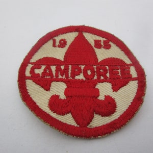 May include: Red and white embroidered patch with a fleur-de-lis and the text "CAMPOREE" and the numbers "1955".