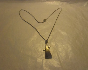 May include: A silver chain necklace with a geometric pendant. The pendant is a triangular shape with a smaller triangle intersecting it.
