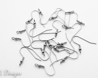 May include: A pile of silver earring hooks with small balls at the top. The hooks are made of metal and are designed for attaching earrings.