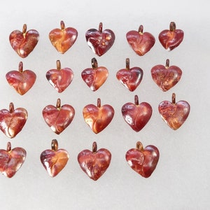 May include: Twenty red and orange heart-shaped pendants with a crackled finish. The pendants are arranged in four rows of five.