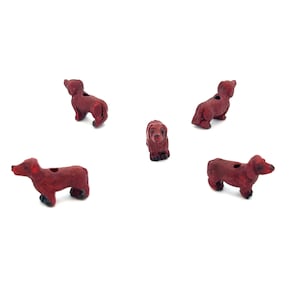 May include: Five red dachshund dog shaped beads. The beads are made of a smooth, hard material and have a hole through the center for stringing.