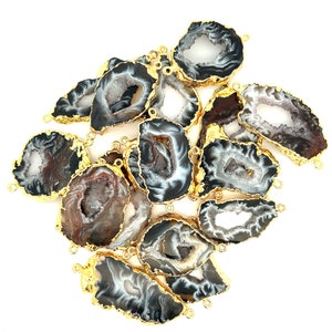 May include: A collection of agate slices with gold-plated edges. The natural stone pieces feature a variety of colors, including gray, white, and brown, with a crystalline center. Each slice has a loop for jewelry making.