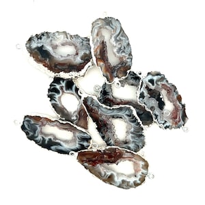 May include: A group of seven agate slices with silver-toned metal accents. The agate slices are brown, black, and white with a natural crystal formation.