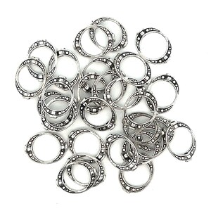 May include: A pile of silver jump rings with a decorative design. The rings are about 1 inch in diameter.