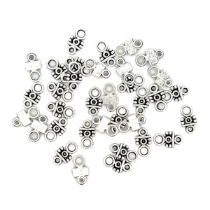 May include: Silver-toned metal connector charms with a decorative design. The charms have two loops on one end and a flat, decorative piece on the other end.