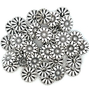 May include: A collection of silver-toned metal buttons shaped like daisies. The buttons have a raised, textured design and a small hole in the center.