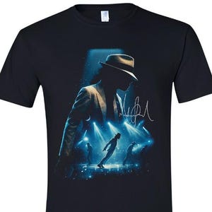 May include: Black t-shirt featuring a silhouette of a person in a suit and fedora, with a stage performance scene in blue and white. Includes a signature in white.