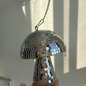 Peut inclure: Une boule disco argentée en forme de champignon avec une chaîne attachée au sommet.