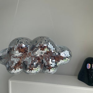 May include: A silver disco ball shaped like a cloud hanging from the ceiling.